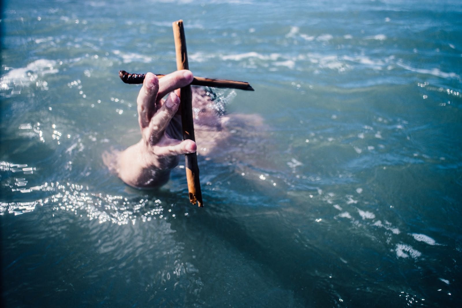 religious freedom person under water holding brown wooden cross above water at daytime