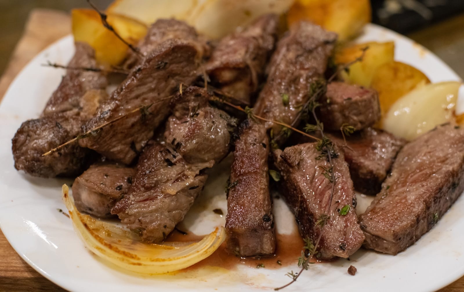 a white plate topped with beef steak and potatoes